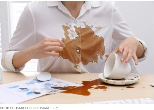 Person spills coffee on white shirt.