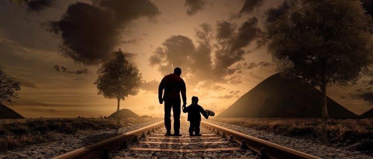 Silhouetted figures on railroad track at sunset.