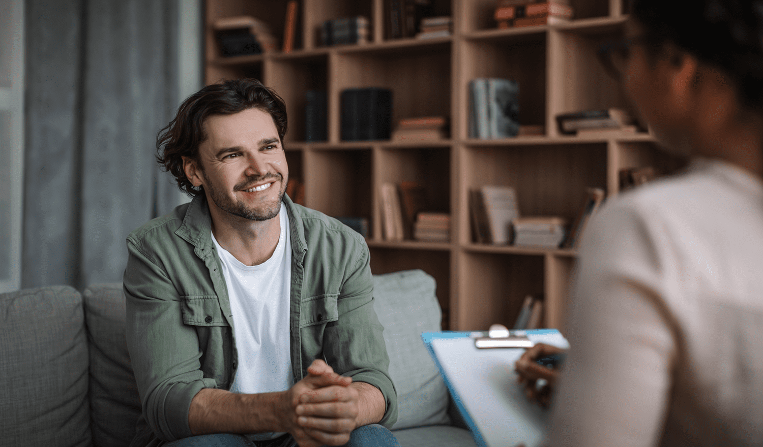 Smiling man speaking with therapist on couch