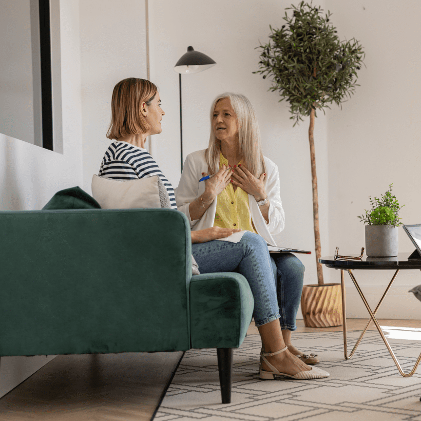Two women conversing on green sofa