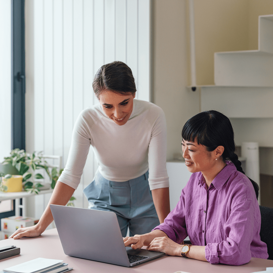 Two women collaborating on laptop in office